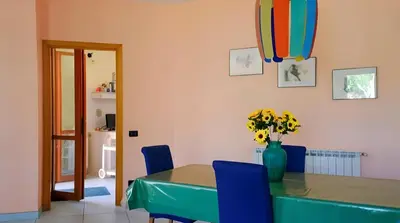 a dining room table with blue chairs and a vase with flowers at Villa Viola e Giulio in Scopello