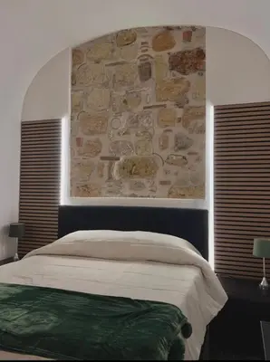 a bedroom with a stone wall and a bed at Ausa 20 - Tra Storia e Mare in Palermo