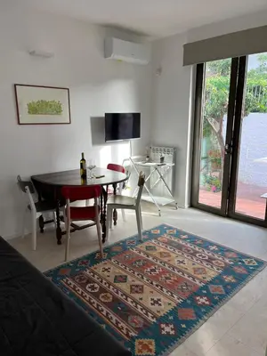 a living room with a dining room table and a rug at Giunone Garden in Palermo