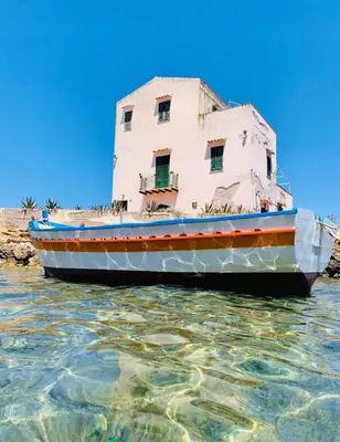 a boat sitting in the water next to a building at Guest House Lo specchio sul mare in Santa Flavia