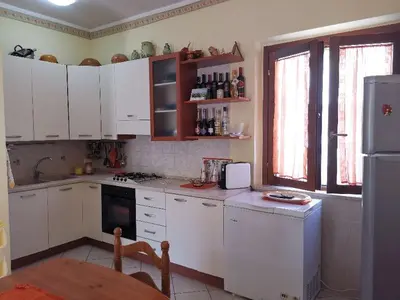a kitchen with white cabinets and a table in it at Endless summer in Castelluzzo