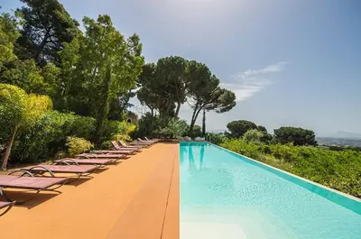 a large swimming pool with lounge chairs and trees at Casa Conigli con piscina condivisa in Terrasini
