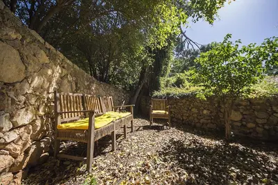 two wooden benches sitting next to a stone wall at Casa Conigli con piscina condivisa in Terrasini