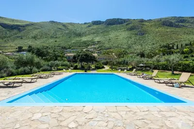 a swimming pool with chairs and mountains in the background at Ulivo Blu Holiday Homes by Wonderful Italy in Castellammare del Golfo