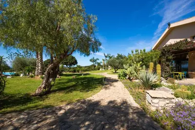 a garden with a tree and a house at Ulivo Blu Holiday Homes by Wonderful Italy in Castellammare del Golfo