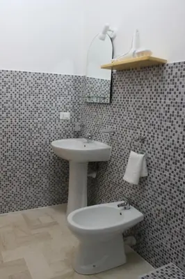 a bathroom with a sink and a toilet and a mirror at Casa Chiarenza in Castellammare del Golfo