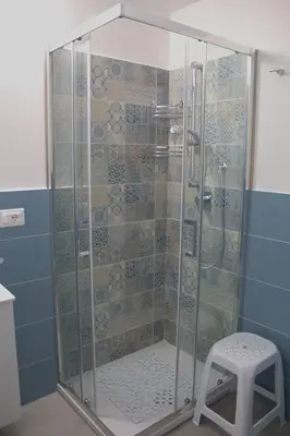 a glass shower with a stool in a bathroom at Bom Bom Apartments in Castellammare del Golfo