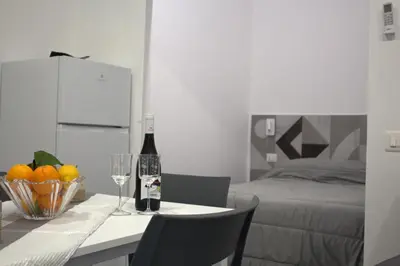 a room with a table with a bottle of wine and a bed at Bom Bom Apartments in Castellammare del Golfo