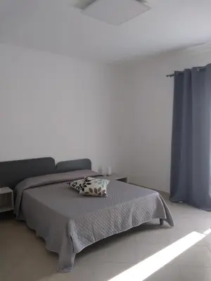 a bedroom with a bed and a blue curtain at Granello di Sabbia in San Vito lo Capo