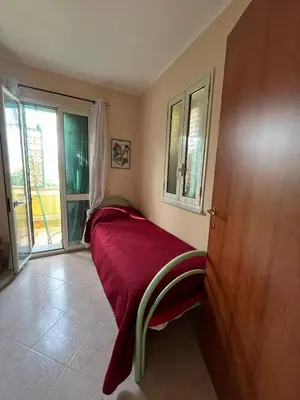 a bedroom with a bed with a red blanket and a window at Casa Marina in Isola delle Femmine