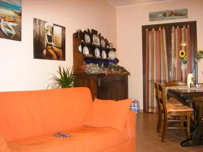 a living room with an orange couch and a table at Baglio Makari in San Vito lo Capo