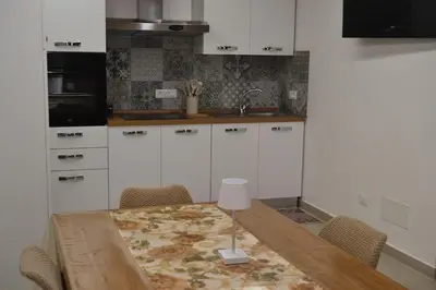 a kitchen with a wooden table and white cabinets at Casa Asprigna in Ficarazzi