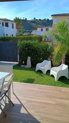 a patio with white benches on the grass at I Giardini del mare casa vacanza in Buonfornello