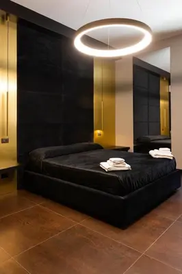 a bedroom with a black bed and a large chandelier at Black Room Suite and SPA in Carini