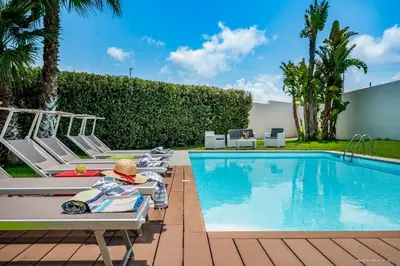 a pool with chaise lounge chairs next to a resort at Oasi delle Nereidi in Alcamo