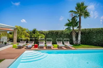 a group of lounge chairs and a swimming pool at Oasi delle Nereidi in Alcamo