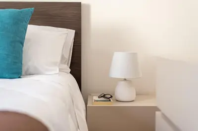 a bedroom with a bed with a lamp on a night stand at Villetta Golfo di Macari 10min San Vito Lo Capo - Horizonte Selections in Castelluzzo