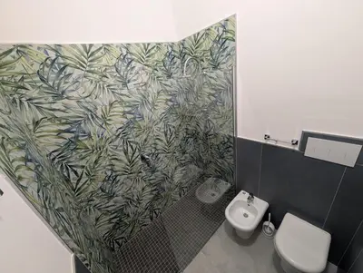 a bathroom with a toilet and a green leafy wallpaper at Nonna Rosa Anna in Isola delle Femmine