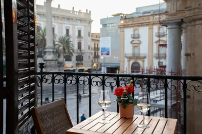a table with two glasses of wine on a balcony at Piano Imperiale Home in Palermo