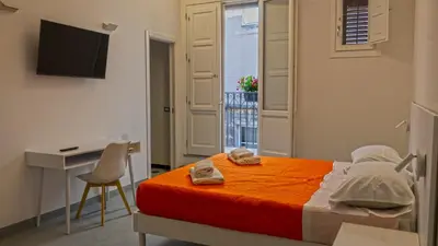 a bedroom with a bed and a desk and a computer at Ostello Vucciria in Palermo