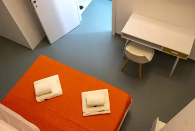 an orange bed with a desk and a chair at Ostello Vucciria in Palermo