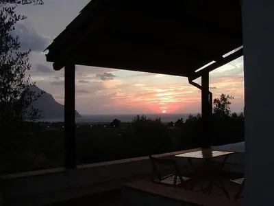 a table and chairs on a porch with a sunset at Casa panorama in Castelluzzo