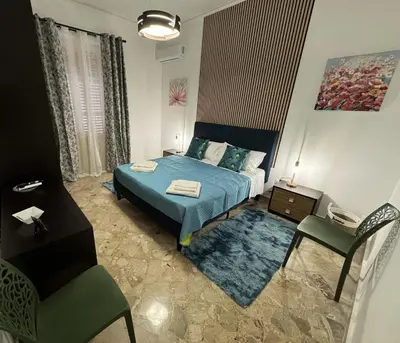 a bedroom with a blue bed and a chair at Beautiful Dimora Anna e Ciccio in Casteldaccia