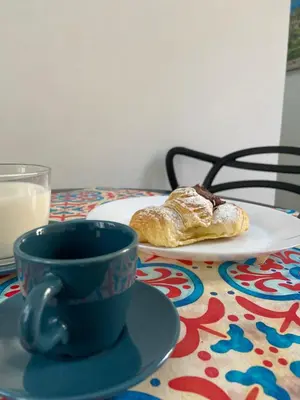 a table with a cup of coffee and a plate of croissants at Sicilia Bedda Room's in Palermo