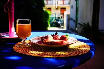 a bowl of strawberries on a table with a glass of beer at A Casa da Mammi in Palermo