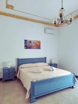 a bedroom with a blue bed and a painting on the wall at A Casa da Mammi in Palermo