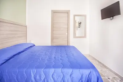 a blue bed in a white room with a tv at B&B La Torre in Castellammare del Golfo