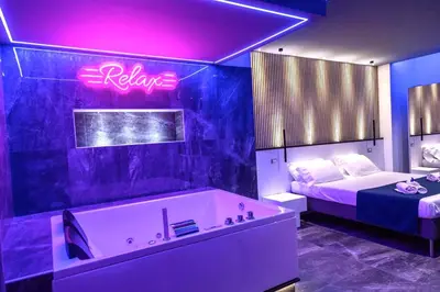 a bathroom with a tub and a bed and a neon sign at B&B Del Centro e SPA in Partinico