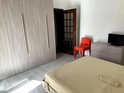a bedroom with a bed and a red chair at Casa Vacanza Mondello nel Cuore in Mondello