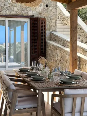 a wooden table with plates and wine glasses on it at Villa Anthea - Relax vista mare tra Palermo e Cefalù in Trabia
