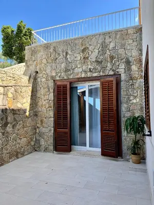 a stone building with wooden doors and a stone wall at Villa Anthea - Relax vista mare tra Palermo e Cefalù in Trabia