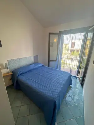 a bedroom with a bed with a blue comforter at San Vito Suite Apartament in San Vito lo Capo