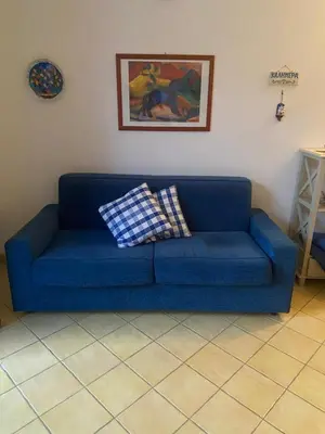 a blue couch in a living room with a picture at San Vito Suite Apartament in San Vito lo Capo