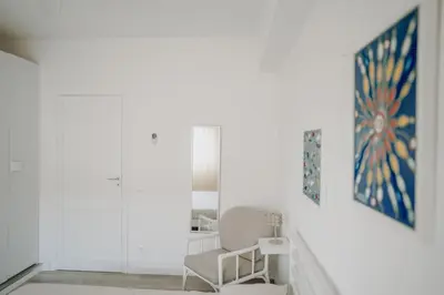 a white room with a chair and paintings on the wall at La Perla d'Argento in Santa Flavia