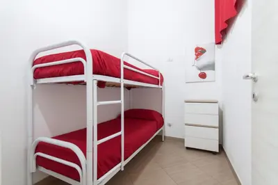 a room with two bunk beds with red sheets at Casa Vacanze del Golfo in Castellammare del Golfo