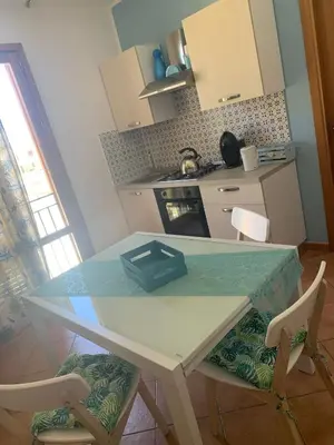 a kitchen with a table and two chairs and a table at La perla marina casa vacanza in San Vito lo Capo
