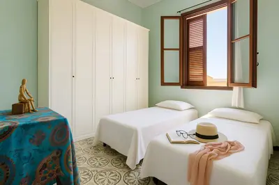 two beds in a room with a hat and glasses at Casa De Gasperi in Castellammare del Golfo