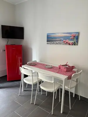 a dining room table with white chairs and a red and white table at Giulia's Apartment in Altavilla Milicia