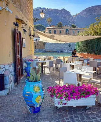 a patio with tables and chairs and vases with flowers at Giomasue' in Porticello