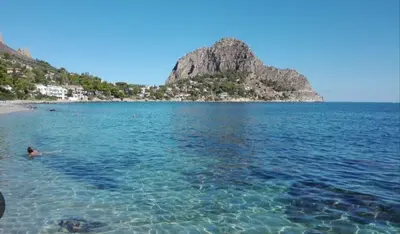 a person swimming in the water near a beach at Giomasue' in Porticello