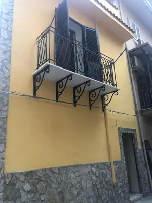a yellow building with a balcony and a window at Mahalo in Palermo