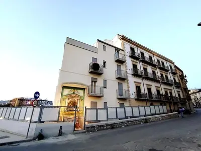 a large white building with a fence in front of it at QASA apartment with terrace, Palermo center in Palermo