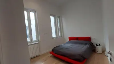 a bed in a white room with two windows at AntoX3 in Palermo