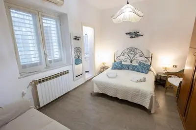 a white bedroom with a bed and two windows at Plaza Del Mar Casa vacanza Mondello in Palermo