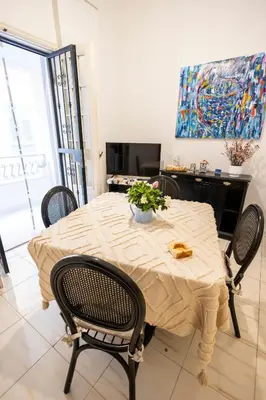 a dining room table with chairs and a painting at Plaza Del Mar Casa vacanza Mondello in Palermo