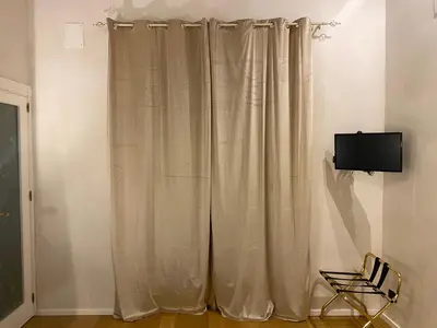 a curtain in a room with a tv and a chair at B&B Duca di Maqueda nel pieno centro dell citta' a 5 minuti dalla stazione degli autobus e dei treni in Palermo